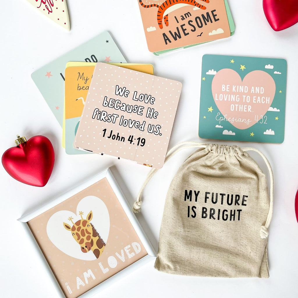 Children's Affirmation card flat lay with a framed affirmation card and a bible verse. "We love because He first loved us." 1 John 4:19